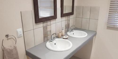 two sinks in a bathroom with two mirrors at Mayfair Farm Cottages in Oudtshoorn