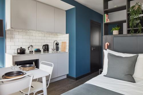a bedroom with a bed and a table and a kitchen at ARK Canary Wharf in London