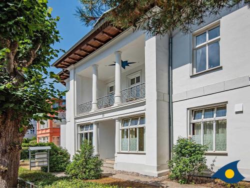 a white house with a balcony and a tree at Villa Linde Whg 06 in Heringsdorf
