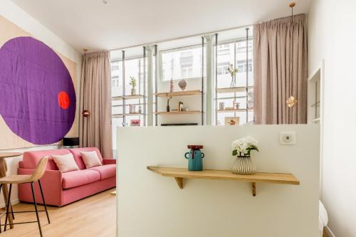 un salon avec un canapé rose et une table dans l'établissement Appartement Panthéon - Feuillantines, à Paris