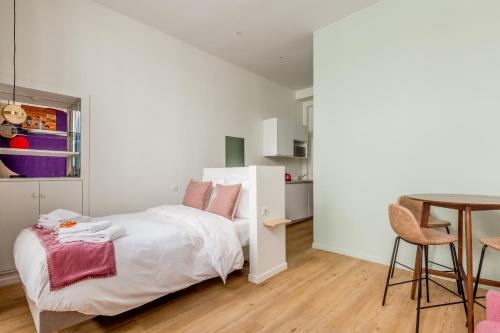 a white bedroom with a bed and a table at Appartement Panthéon - Feuillantines in Paris