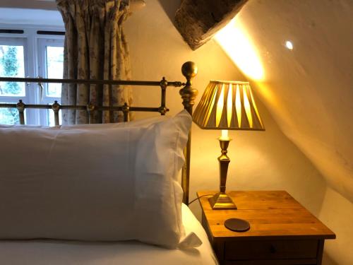 a bed with a pillow and a lamp on a table at Traditional 18th Century Farmhouse in Streatley in Streatley