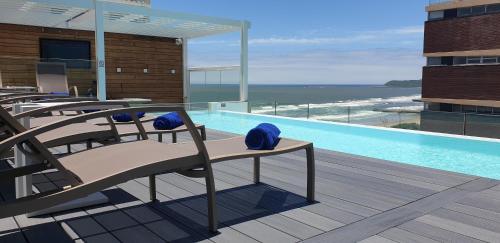 a resort with a pool with chairs and the ocean at Blue Waters Hotel in Durban