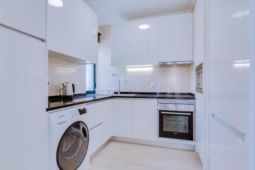 a white kitchen with a washing machine in it at Tália - City Center - Vilamoura in Vilamoura