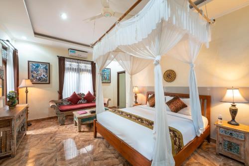 a bedroom with a canopy bed and a living room at Ashanti Villa Ubud in Ubud