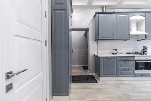 eine Küche mit grauen und weißen Schränken und einer Spüle in der Unterkunft InshiApartments on Lysenka str in Lwiw