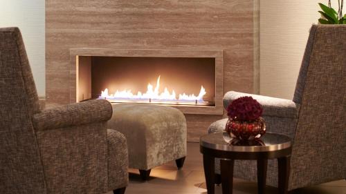 a living room with two chairs and a fireplace at The Mandala Berlin, a Member of Design Hotels in Berlin
