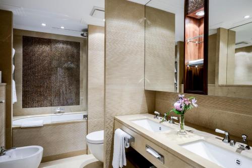 a bathroom with two sinks and a toilet and a tub at Hotel Bayerischer Hof in Munich