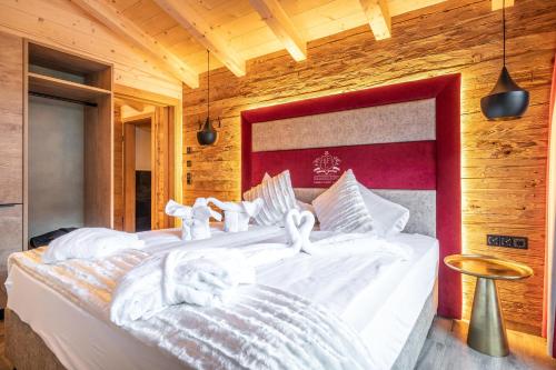 a bedroom with a large bed with white sheets at The Kaprun Edition - Luxury Chalets & Style Suites in Kaprun