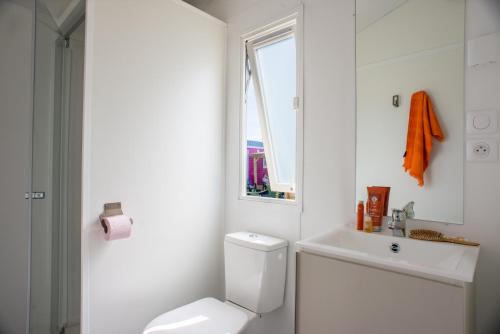 La salle de bains blanche est pourvue de toilettes et d'un lavabo. dans l'établissement Camping Emeraude, à Saint-Briac-sur-Mer