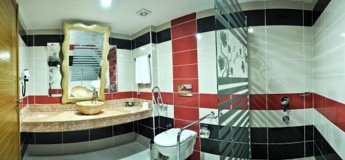 a bathroom with a red and white tiled wall at Demosan Hotel in Karaman