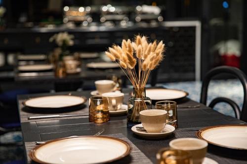 a table with plates and cups and a vase with feathers at Solaria Hanoi Hotel in Hanoi