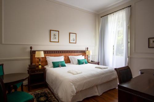 a bedroom with a large white bed with a window at Hotel Solar do Império in Petrópolis