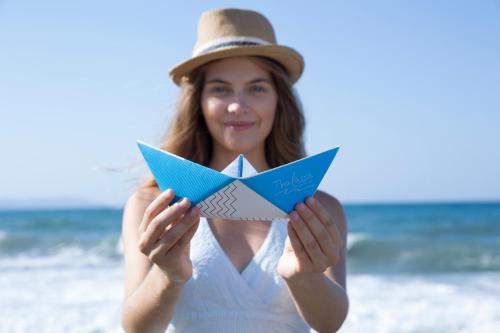 a woman on the beach holding a paper boat at Thalassa Beach Resort & Spa (Adults Only) in Agia Marina Nea Kydonias