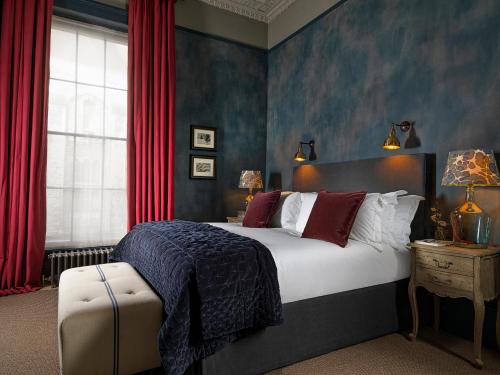 a bedroom with a large bed with red curtains at No131 The Promenade in Cheltenham