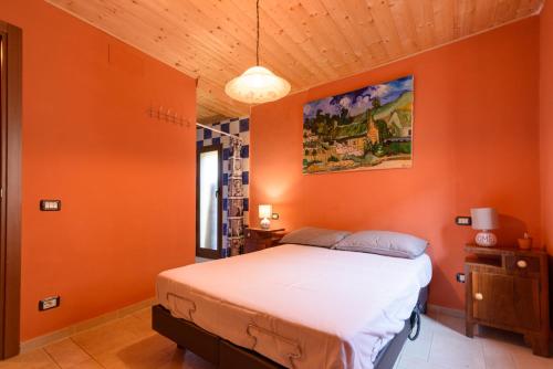 a bedroom with an orange wall with a bed at La maison de Martine in Bolognano