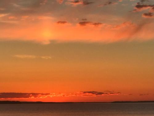 an orange sunset over the ocean with the sky at Les pieds dans le sable in Chambord