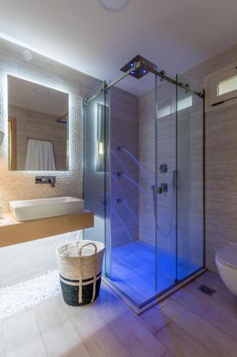 a bathroom with a glass shower with a tub and a sink at Stelios Gardens in Malia