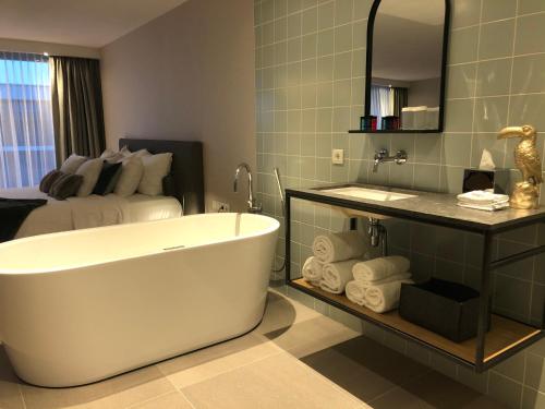 a bathroom with a tub, toilet and sink at Van der Valk Hotel Sassenheim - Leiden in Sassenheim