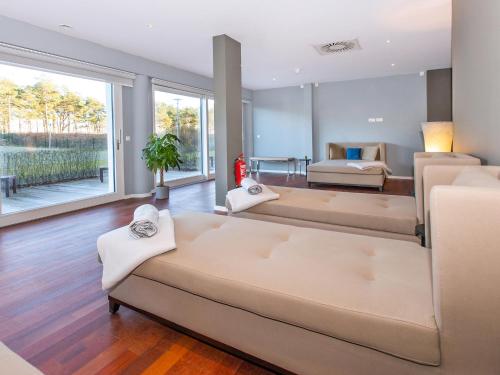 ein Wohnzimmer mit einem großen Sofa und einem Bett in der Unterkunft DORMERO Strandhotel Rügen in Binz