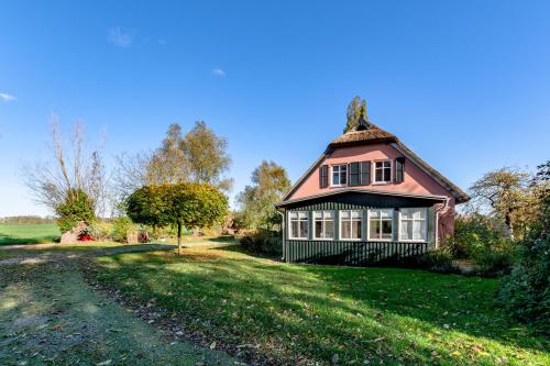 a large house with a red roof on a green field at Hof Garz in Poseritz