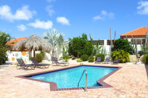 a swimming pool with chairs and a resort at Kunuku Villa in Oranjestad