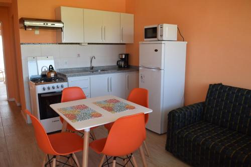 a kitchen with a table and chairs and a white refrigerator at Apart Hotel Terrazas de San Francisco in Piriápolis