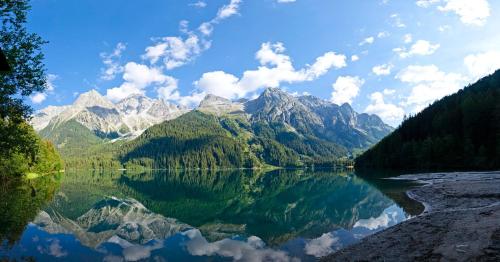 un reflejo de montañas en un cuerpo de agua en Apartment Antholzersee, en Anterselva di Mezzo
