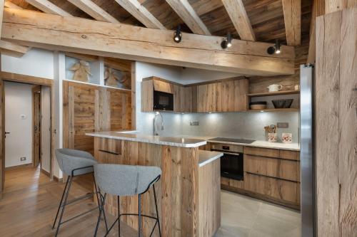 une cuisine avec des armoires en bois et un comptoir avec des tabourets dans l'établissement Penthouse Flèche - LES CHALETS COVAREL, à Val dʼIsère
