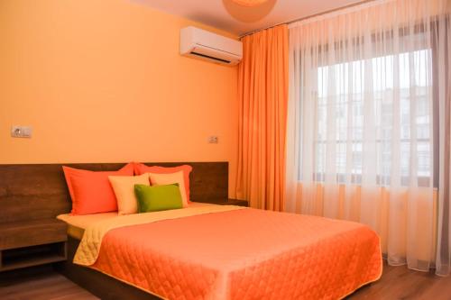 1 dormitorio con cama de color naranja y ventana en Sunny en Burgas