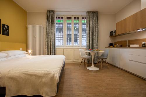 a bedroom with a bed and a table and a kitchen at Aqualago casa vacanze apartment A in Verbania