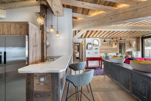 - une cuisine avec des plafonds en bois et un comptoir avec des tabourets dans l'établissement Penthouse Chamois - LES CHALETS COVAREL, à La Daille