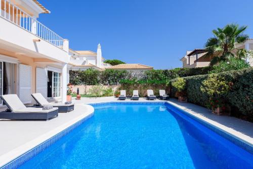 a swimming pool with chairs and a house at Casa Lago in Quinta do Lago