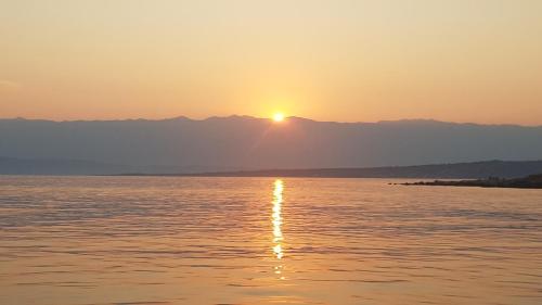 a sunset over the water with mountains in the background at Apartment Lavanda garden in Rab