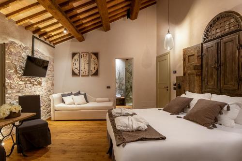 sypialnia z dużym białym łóżkiem i kanapą w obiekcie Borgo Antichi Orti Assisi w Asyżu