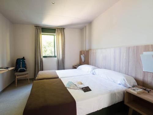 a hotel room with two beds and a window at Albergue Monte Do Gozo in Santiago de Compostela