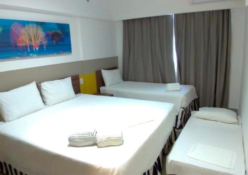 deux lits dans une chambre d'hôtel avec des draps blancs dans l'établissement Apartamento em Resort de Olimpia, à Olímpia