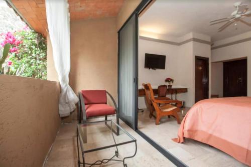 a bedroom with a bed and a chair and a table at Orchidelirium Casa Hotel & Salud Estética in Cuernavaca