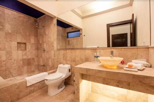 a bathroom with a toilet and a sink and a tub at Orchidelirium Casa Hotel & Salud Estética in Cuernavaca