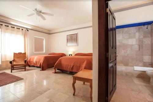 a bedroom with two beds and a bathroom at Orchidelirium Casa Hotel & Salud Estética in Cuernavaca