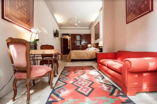 a living room with a red couch and a dining room at Orchidelirium Casa Hotel & Salud Estética in Cuernavaca