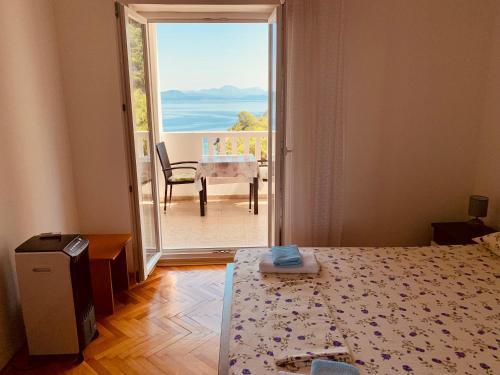 a bedroom with a bed and a door to a balcony at Guest House Ruža in Sobra
