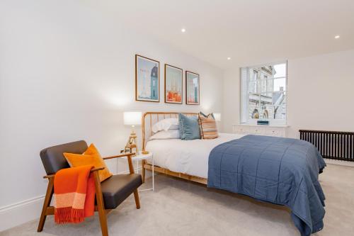 a bedroom with a bed and a chair and a window at Oxfordshire Living - The Churchill Apartment - Woodstock in Woodstock