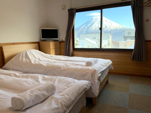 two beds in a room with a view of a mountain at Pension Berg in Niseko