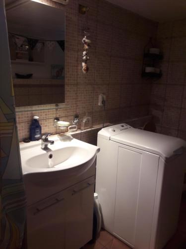 a bathroom with a sink and a white refrigerator at Bela apartment in Belá