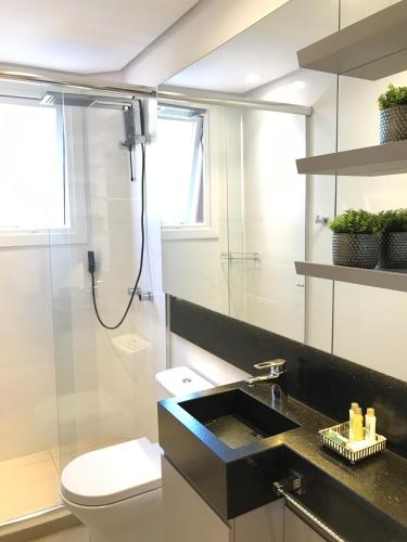 a bathroom with a sink and a toilet and a shower at Apartamento Vêneto in Canela