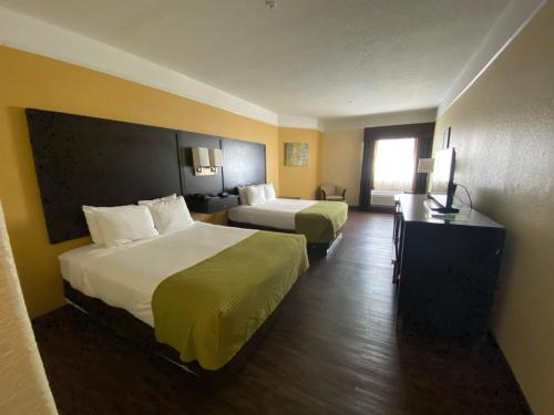 a hotel room with two beds and a television at Galveston Beach Hotel in Galveston