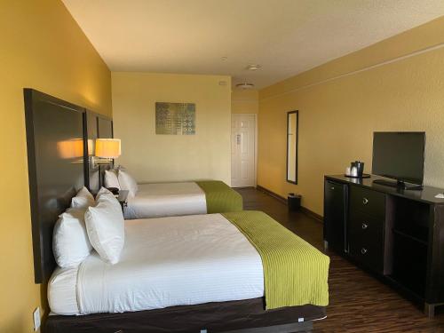 a hotel room with two beds and a flat screen tv at Galveston Beach Hotel in Galveston