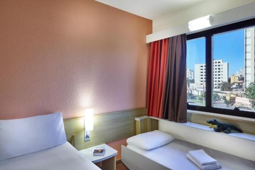 um quarto de hotel com uma cama e uma janela em ibis Taubate em Taubaté