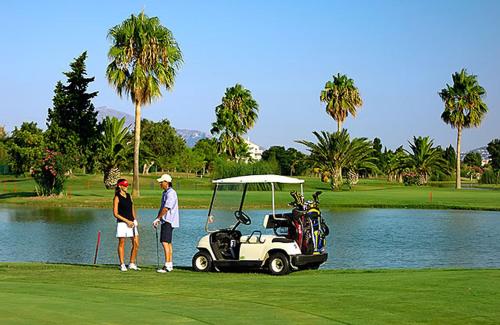 a man and a woman standing next to a golf cart at OLIVA NOVA GOLF BEACH & RESORT club sevilla II in Oliva